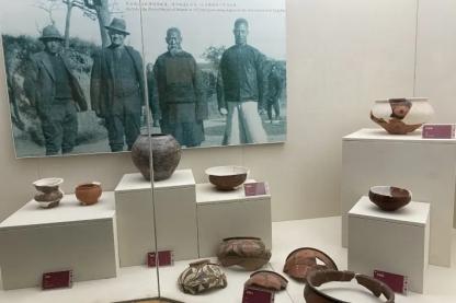 picture of Johan Gunnar Andersson (2nd from left) behind pottery exhibits